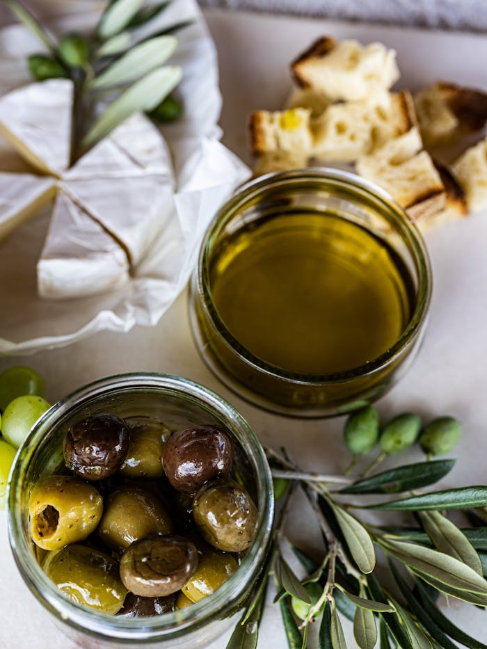 Top-down view of Mediterranean olives, cheese, and olive oil with bread.